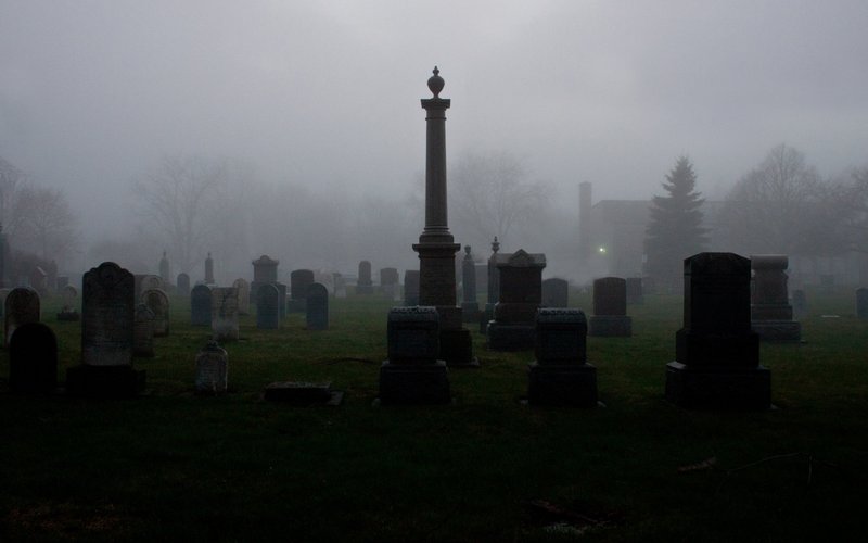 Grabsteine auf einem Friedhof, verregnete Morgendämmerung