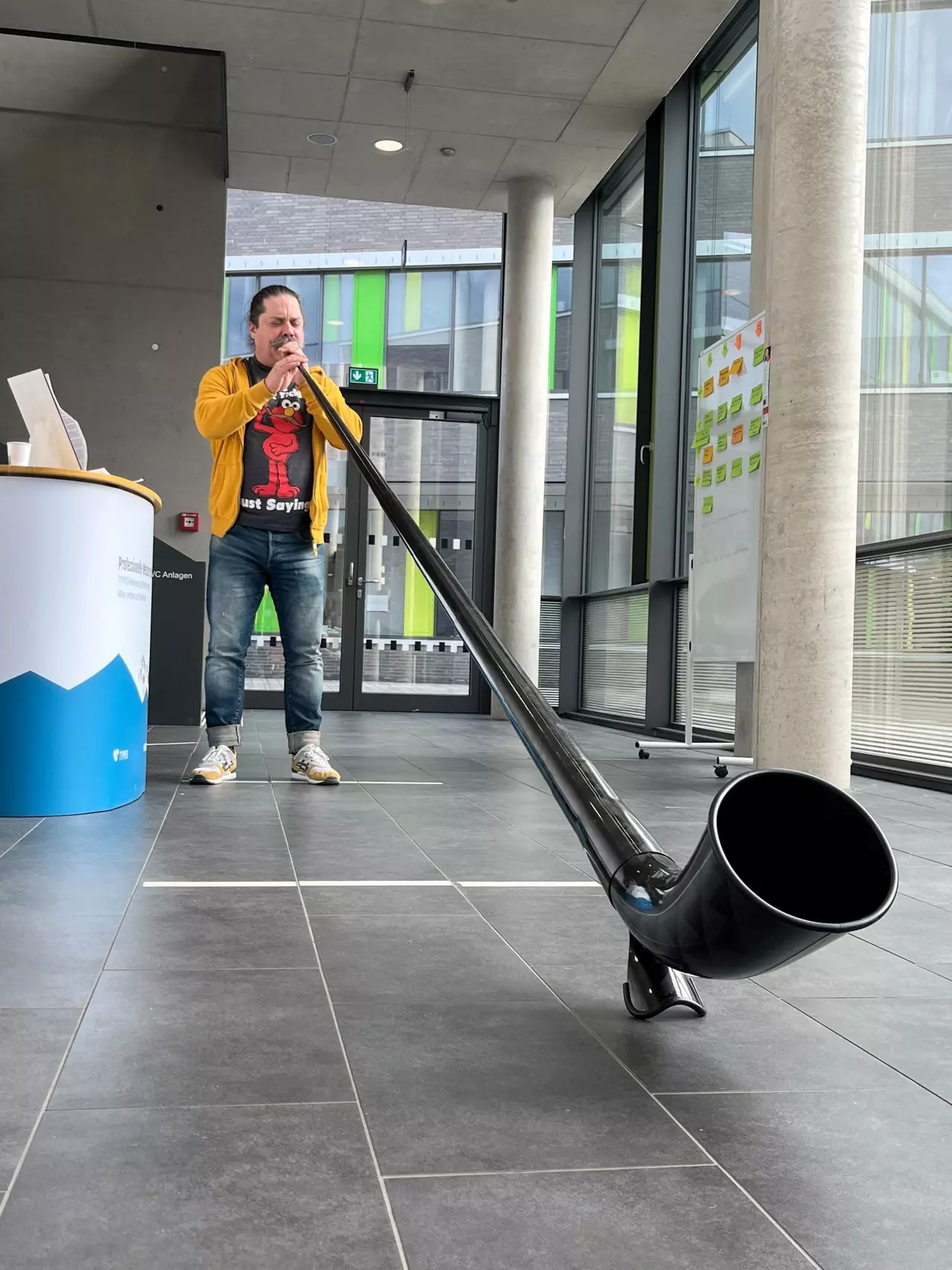 Jeffrey A. McGuire spielt ein Alphorn im Eingangsbereich des Camps