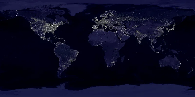 Eine Weltkarte bei Nacht aus dem Weltraum. Helle Lichter markieren die städtischen Gebiete und Kontinente Nord- und Südamerika, Europa, Afrika, Asien sowie Australien vor dem dunklen Hintergrund der Ozeane.